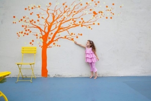 Girl pointing to orange tree mural on wall
